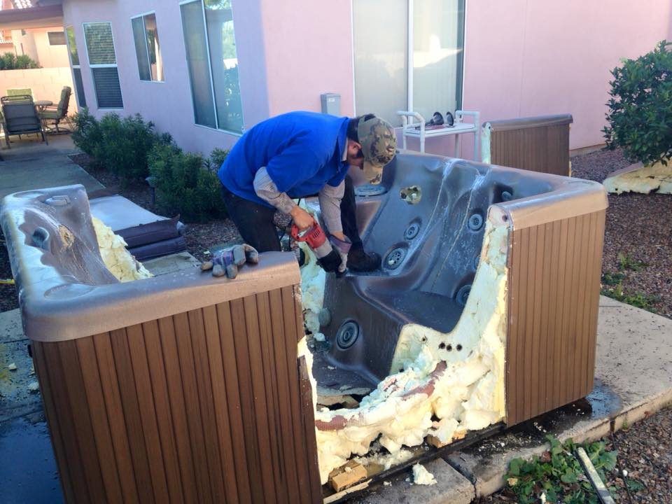 A man and woman are working on the back of a hot tub.
