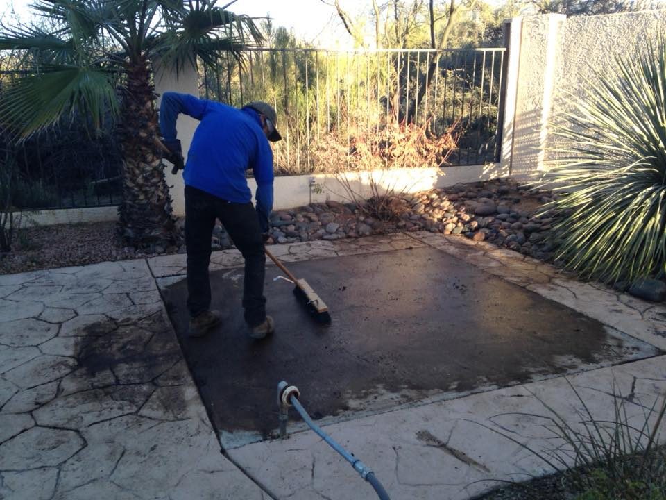 A man is cleaning the concrete on the patio.