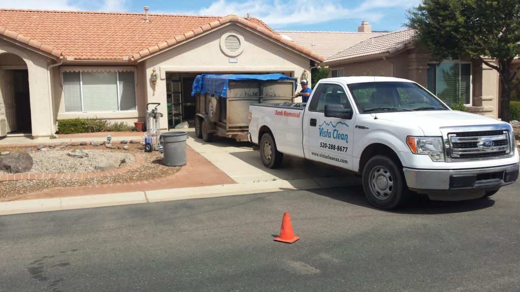 A Vista Clean Junk Removal truck and trailer on a job in Tucson loaded in front of a house