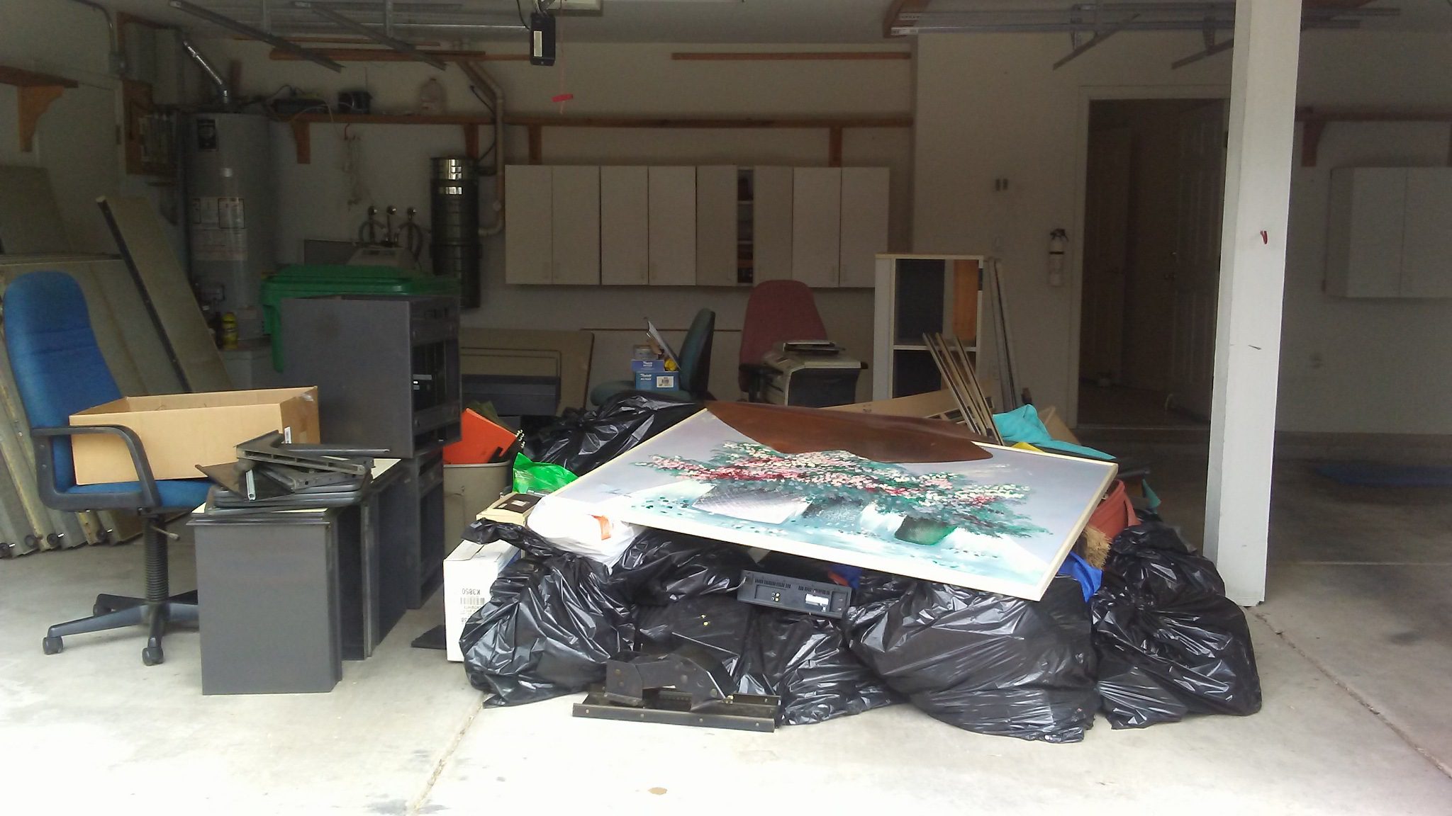 A garage with garbage bags and boxes on the floor.