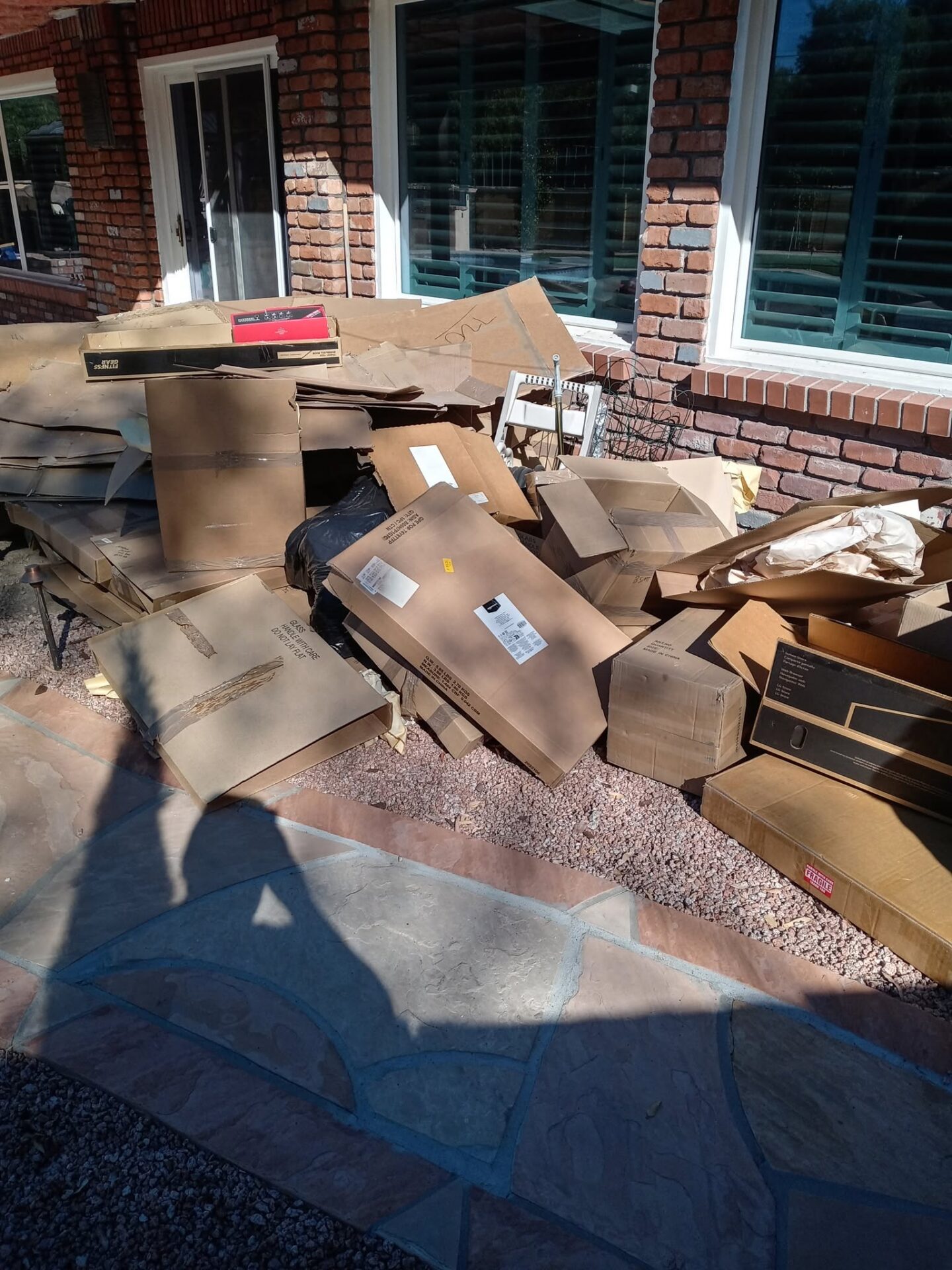 A before photo of a front yard filled with old cardboard boxes in Casas Adobes, AZ