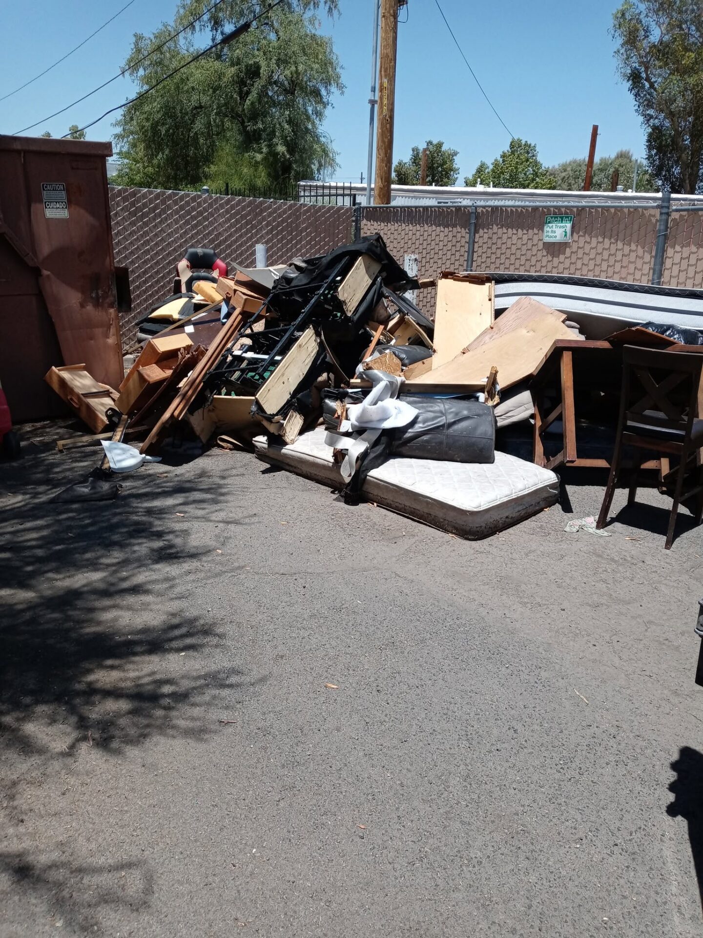 A before photo of a bunch of debris, boxes and pallets at a property in Drexel Heights, AZ