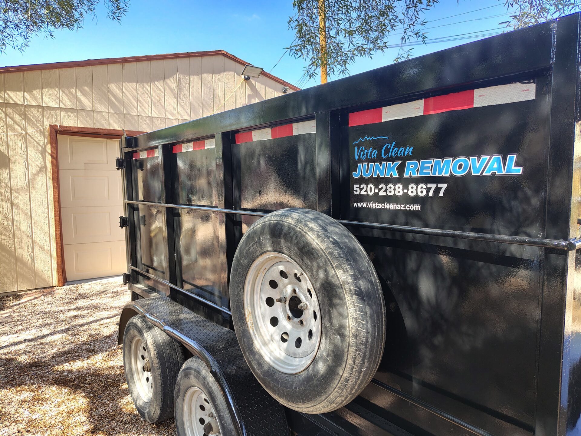 a picture of a vista clean junk removal trailer on a property with a house and garage in the background