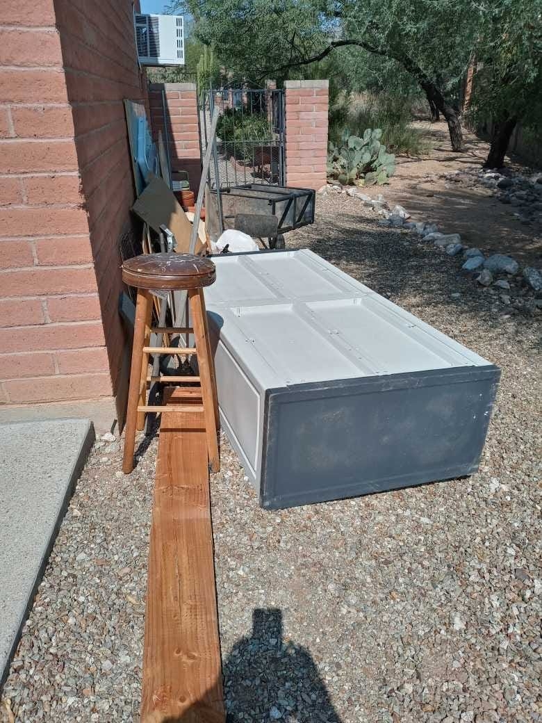Phot of a yard in Green Valley, AZ with a cabinet, boards and other random items
